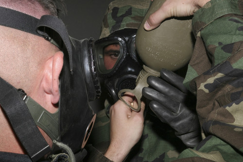 November 22, 2005 - A nuclear, biological and chemical defense specialist assists another Marine in helping him fit his gas mask's drinking tube into his canteen. Poster Print - Item # VARPSTSTK102525M