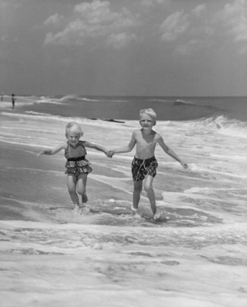 Boy and girl holding hands and running on the beach Poster Print - Item # VARSAL25547954