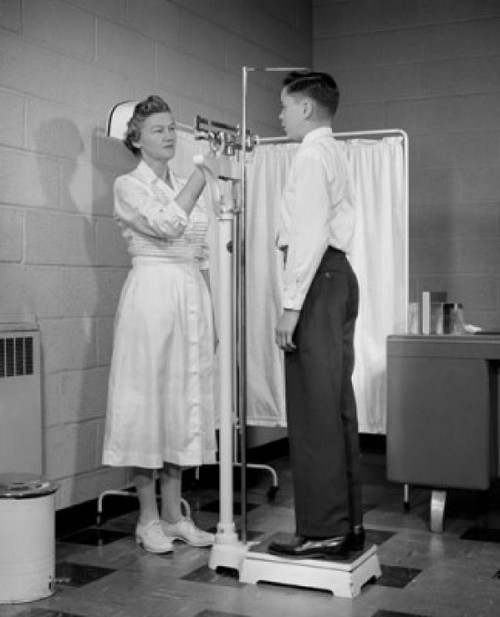 Female nurse measuring height and weight of a boy Poster Print - Item # VARSAL25526451