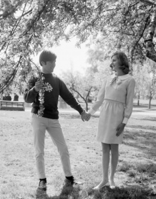 Young couple standing under tree holding hands Poster Print