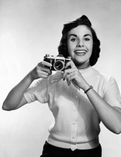 Female photographer holding a camera and smiling Poster Print - Item # VARSAL2557794