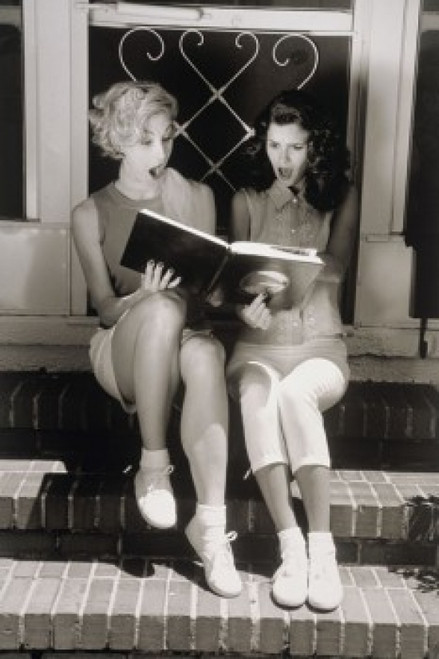 Two young women looking at photo album Poster Print - Item # VARSAL1073103