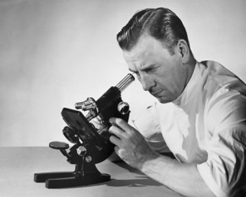 Male researcher looking through a microscope Poster Print