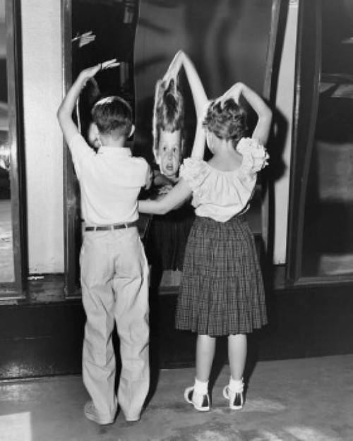 Rear view of boy and girl looking in fun mirror Poster Print - Item # VARSAL255974