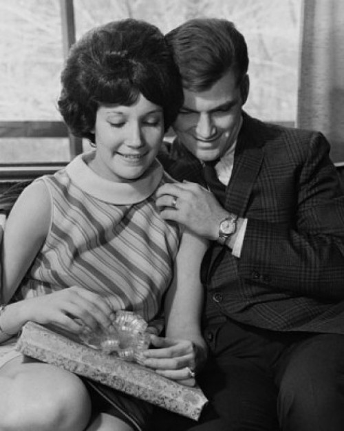 Young woman holding a gift and sitting with a young man Poster Print - Item # VARSAL25539875 Young woman holding a gift and sitting with a young man Poster Print - Item # VARSAL25539875