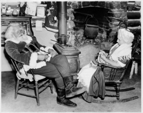 Side profile of Santa Claus sitting with a senior woman near a fireplace Poster Print - Item # VARSAL255690