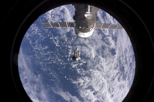 November 5, 2007 - Space Shuttle Discovery backdropped by a blue and white Earth. A Russian spacecraft docked to the station is visible at top Poster Print