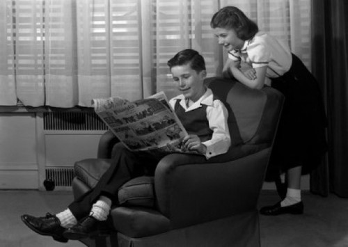 Boy reading comic in armchair  with girl peeking over shoulder Poster Print - Item # VARSAL25516393