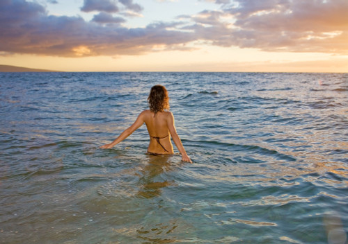 Hawaii, Kauai, Woman Walking In The Ocean As The Sun Sets. PosterPrint - Item # VARDPI1975927