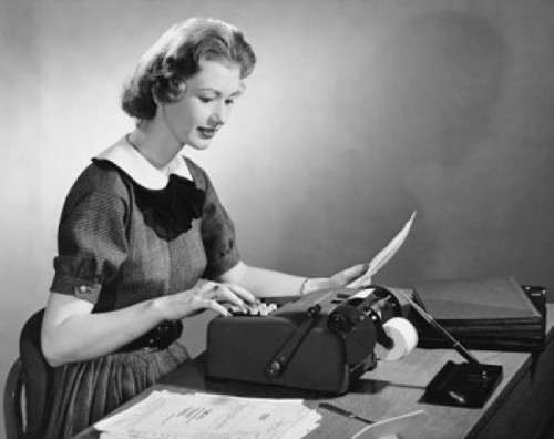 Businesswoman typing on a typewriter in an office Poster Print