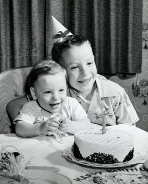 Two boys sitting in front of a birthday cake and smiling Poster Print