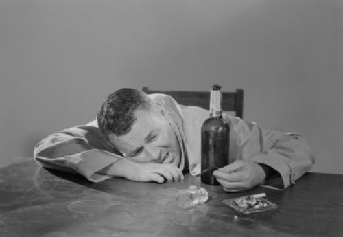 Drunk man sitting behind table Poster Print