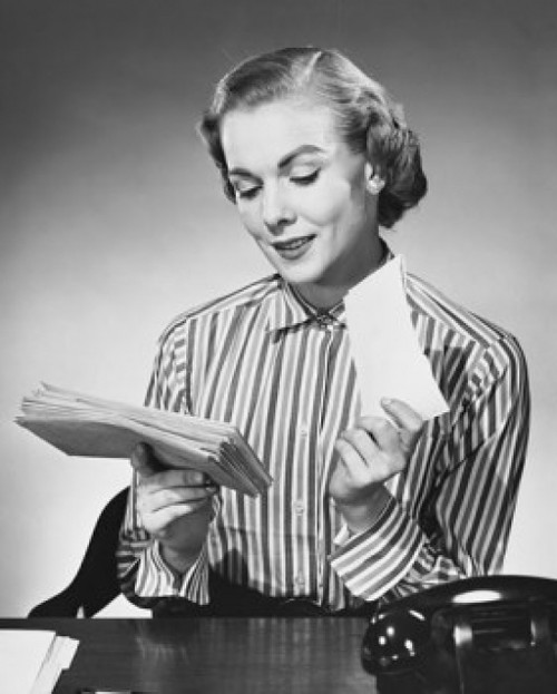 Businesswoman sitting at a desk and holding letters in an office Poster Print - Item # VARSAL25548457
