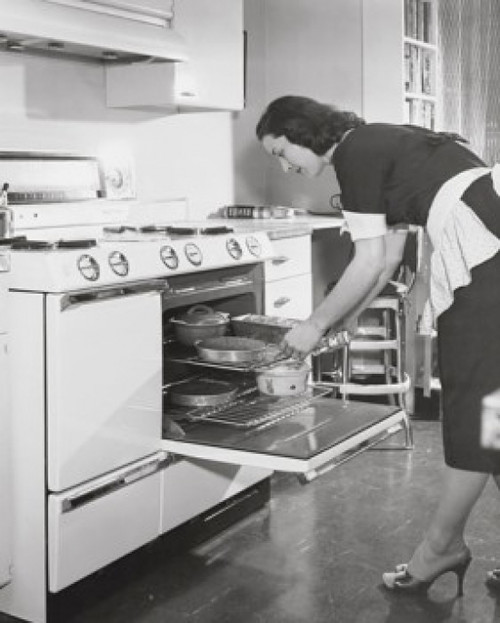 Mid adult woman putting food into an oven Poster Print - Item # VARSAL25536126