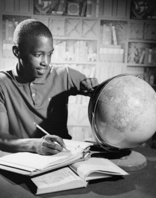 Teenage boy looking at a desktop globe and writing in a notepad Poster Print - Item # VARSAL2553421