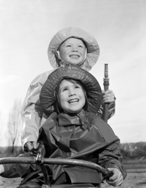Brother and sister wearing rain coats and holding garden hose Poster Print - Item # VARSAL255424457