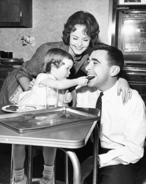 Girl feeding a cookie to her father with her mother looking at them Poster Print - Item # VARSAL25542741