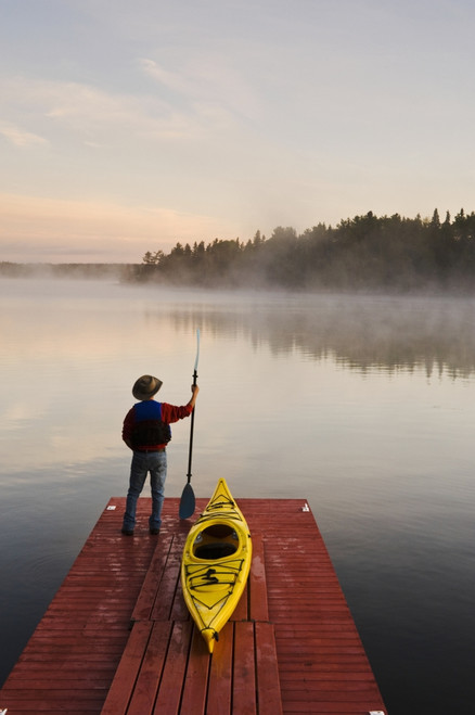 Man Standing By Kayak On Dock In Northwestern Ontario; Lake Of The Woods Ontario Canada PosterPrint - Item # VARDPI2092396