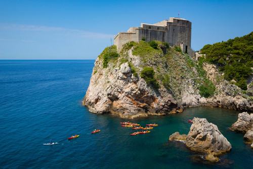 Dubrovnik, Dubrovnik-Neretva County, Croatia. Fort Lovrijenac or St. Lawrence Fortress. Canoeists in harbour. The old city of Dubrovnik is a UNESCO World Heritage Site. Poster Print by Panoramic Images - Item # VARPPI170120