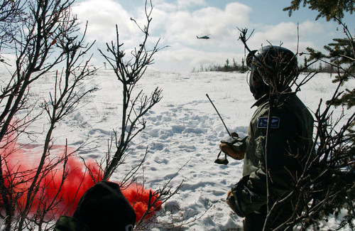 A soldier uses red smoke to signal the nearby HH-60 Pave Hawk helicopter Poster Print by Stocktrek Images - Item # VARPSTSTK102709M