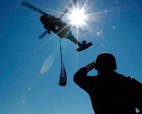 Soldier observes a UH-60 Blackhawk as it prepares to drop slingloaded prepackaged food Poster Print by Stocktrek Images - Item # VARPSTSTK101125M