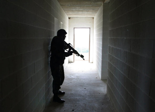 A soldier clears a hallway in a building at a Military Operation in Urban Terrain training facility Poster Print by Stocktrek Images - Item # VARPSTSTK100567M