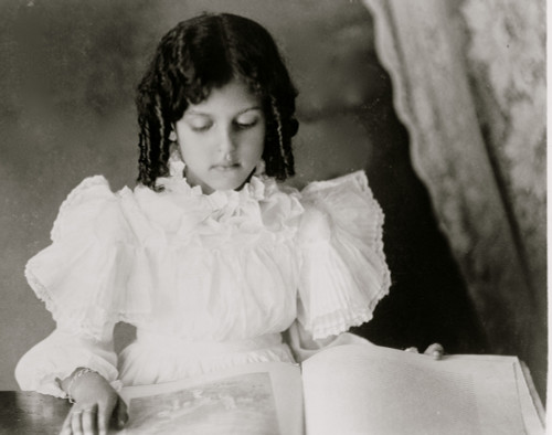 African American girl, half-length portrait, standing at table with illustrated book, facing slightly right Poster Print - Item # VARBLL0587634499