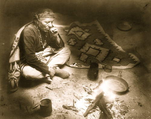 Navajo Indian, seated by campfire, smoking cigarette. Poster Print