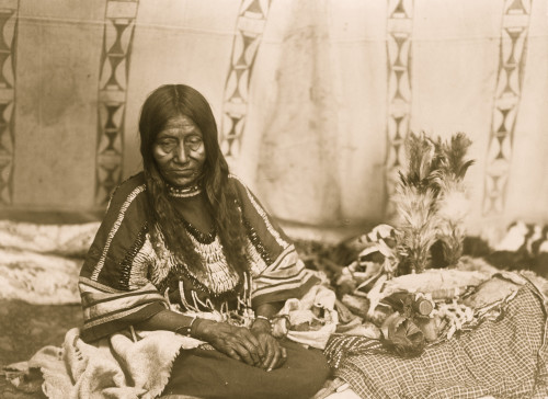 Piegan woman, full-length portrait, seated on blankets inside tipi, facing front. Poster Print - Item # VARBLL058747682L