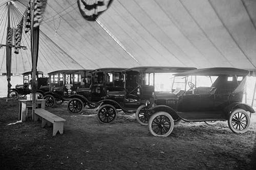 Automobiles & Trucks on Display in Tent Under American Flag Banners Poster Print by unknown