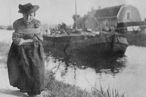 A Older Dutch woman has a bustle around her chest as she pulls a barge down a canal. Poster Print by unknown - Item # VARBLL058745910L