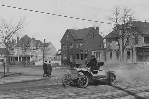 Auto Trundles down city street with its driven in open carriage bundled up Poster Print - Item # VARBLL058746153L
