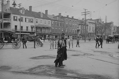 African American Youth Carries a line of fish to sell on the city streets Poster Print - Item # VARBLL058746143L