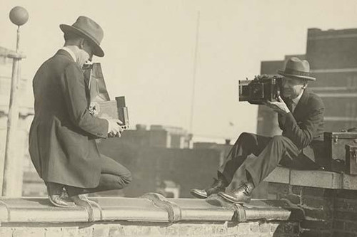 Two photographers taking each others' picture with hand-held cameras while perched on roof Poster Print by unknown - Item # VARBLL058745962L