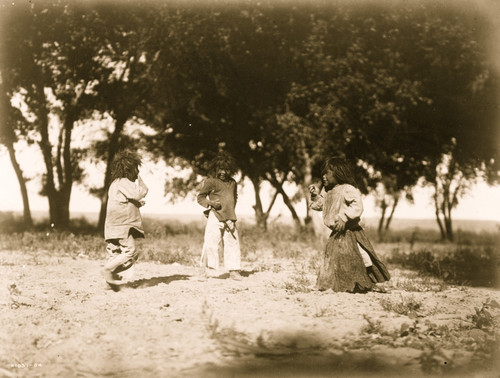 Three Navajo children playing, cottonwoods silhouetted in background. Poster Print - Item # VARBLL058747476L