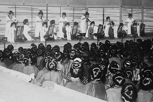 Hairdressers on Stage Compete against one another in making the best hairstyle in the best time while an audience of costumed Japanese ladies look on. Poster Print by unknown - Item # VARBLL058745852L
