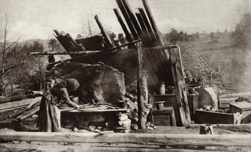 World War 1. Russian Peasant Woman In Her Battle Ruined Home On The Eastern Front. She Placed Her Baby In The Cradle At Right And Is Attempting To Prepare A Meal. Ca. 1915. History - Item # VAREVCHISL034EC703