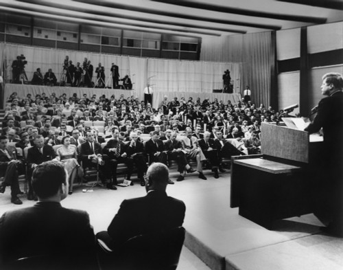 President John Kennedy Speaks To Reporters During A Press Conference. Press Secretary Pierre Salinger And Associate Press Secretary Andrew Hatcher Sit Near The Podium At State Department Auditorium History - Item # VAREVCHISL033EC884