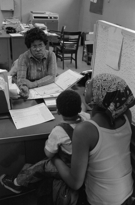 An African American Woman With A Child On Her Lap Talking To A Case Worker At A New York City Welfare Office. May 14 1976. History - Item # VAREVCHISL029EC115