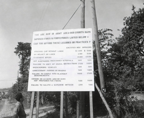 U.S. Soldier Reads Table Of Crimes And Fines For Misconduct In Normandy. The Sign Lists The Offense History - Item # VAREVCHISL038EC048