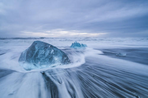 Large ice block laying on the shores of Southern Iceland while waves crash on shore; Iceland Poster Print by Robert Postma / Design Pics - Item # VARDPI12550352