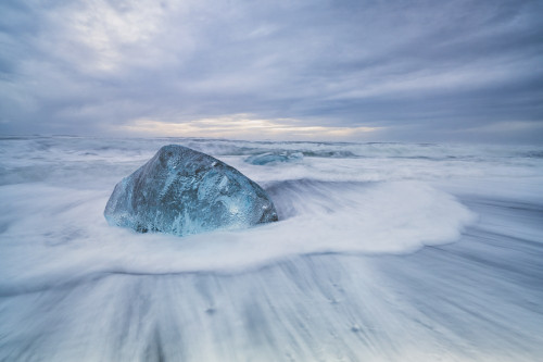 Large ice block laying on the shores of Southern Iceland while waves crash on shore; Iceland Poster Print by Robert Postma / Design Pics - Item # VARDPI12550351