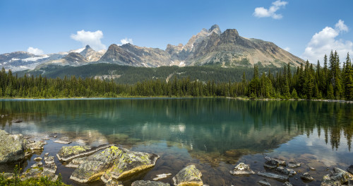 Mountain range reflecting on an alpine lake with a rocky shoreline and blue sky and clouds; British Columbia, Canada Poster Print by Michael Interisano / Design Pics - Item # VARDPI12546273