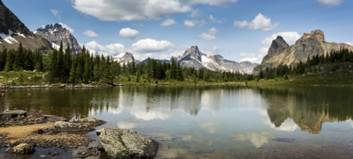 Mountain range reflecting on an alpine lake with a rocky shoreline and blue sky and clouds; British Columbia, Canada Poster Print by Michael Interisano / Design Pics - Item # VARDPI12546272