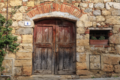 Italy, Monteriggioni. Stone wall, wooden door with planted geraniums. Poster Print by Emily Wilson - Item # VARPDDEU16EWI0477