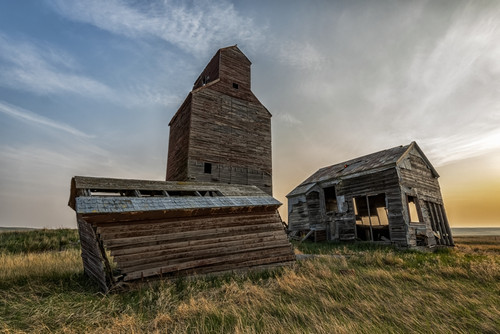 Weathered grain elevator and barns on the prairies at dusk; Neidpath, Saskatchewan, Canada Poster Print by Robert Postma # 12577828