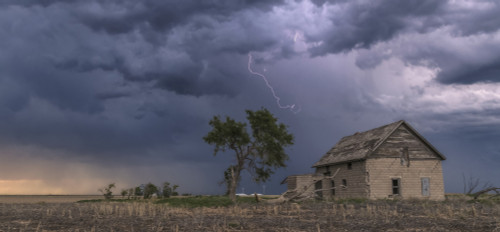 A forked lightning bolt descends from a weak thunderstorm near an abandoned building; Guymon, Oklahoma, United States of America Poster Print by Stuart Short (20 x 9) # 12589965