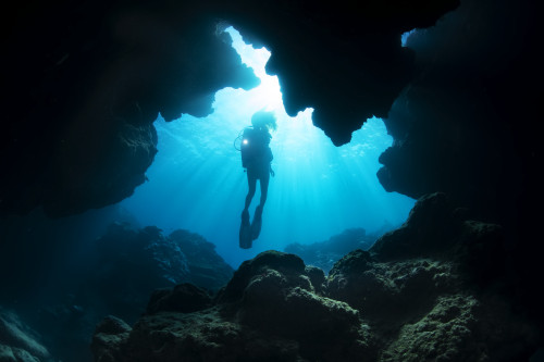 Diver entering a crevice at Yap Cavern�s off the very south end of the island of Yap; Yap, Micronesia Poster Print by Dave Fleetham (19 x 12) # 12576252