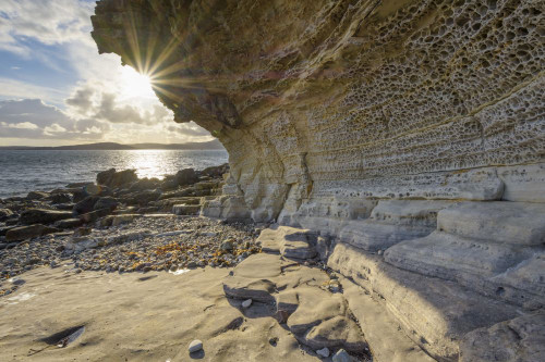 Close-up of rock face of sea cliff with honeycomb weathering and sun shining over Loch Scavaig on the Isle of Skye in Scotland, United Kingdom Poster Print by Raimund Linke (20 x 13)