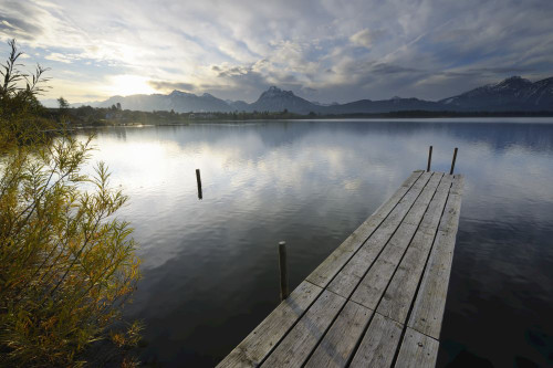 Wooden Jetty with Sun, Hopfen am See, Lake Hopfensee, Bavaria, Germany Poster Print by Raimund Linke (19 x 12)